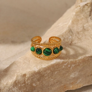Detailed macro view of 18K gold ring with green natural stones on rock