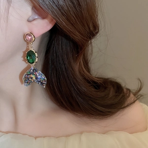 Detail of mermaid tail earrings with sparkling sequins and pink green crystals