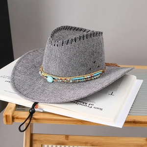 Détail d'un chapeau de cowboy en paille grise avec bande ethnique perlée et turquoise