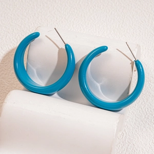 Polished blue acrylic C-shape hoop earrings with metal studs on white display