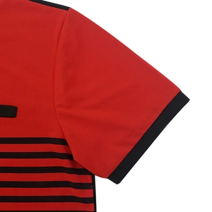 Close-up of red polo shirt showing knit cotton texture, black stripes, and sleeve stitching