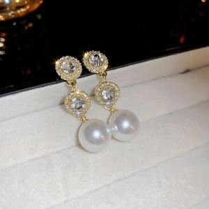 Macro shot of gold earrings with sparkling crystals and a large white pearl drop