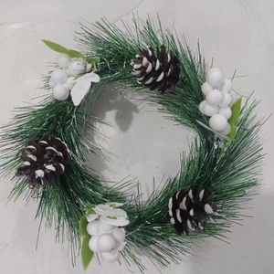 Mini Christmas wreath with green pine needles, white berries and snow-dusted pinecones