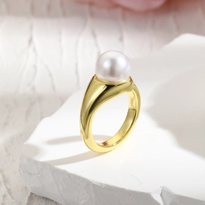 18k gold plated open ring with a round pearl set on a white textured stone base
