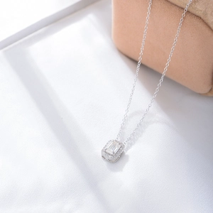 Detail of emerald-cut zircon necklace on white silk fabric showing a classic silver design