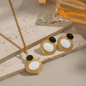 Set collana e orecchini dorati con dettagli geometrici ovali bianchi e neri con texture