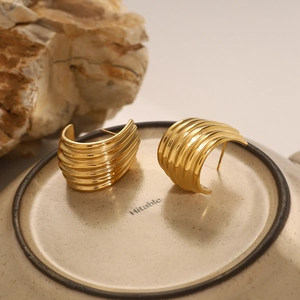 Macro detail of gold chunky ribbed hoop earrings with polished metallic texture