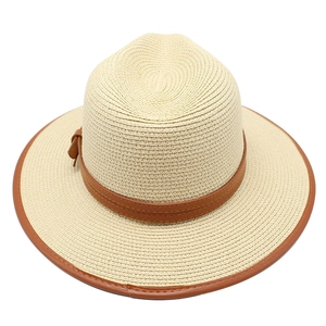 Détail d'un chapeau de paille beige avec ruban en cuir marron et boucle métallique