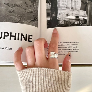 Close-up of minimalist silver irregular wide-surface ring worn on hand with cozy knitwear