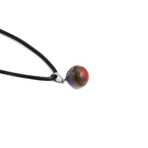 Macro di un ciondolo sferico in pietra striata con collana in corda di cera intrecciata