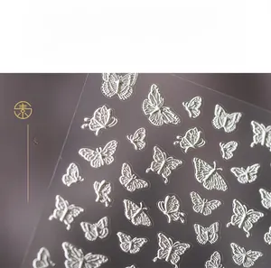 Gros plan de stickers ongles papillon 3D blancs avec relief sur fond violet doux
