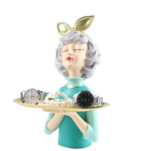 Detail of mint green girl figurine with golden tray for jewelry and watch storage