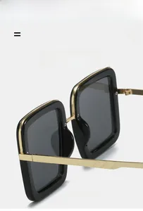 Detail van zwarte vierkante zonnebril met gouden neusbrug en metalen pootjes met textuur