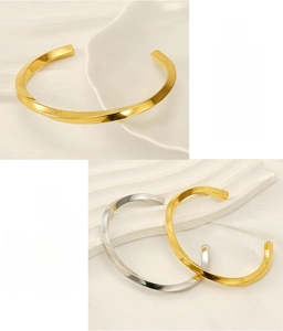 Detail of twisted C-shaped stainless steel bracelets in gold and silver finish