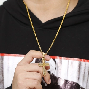 Macro view of golden cross pendant with twisted chain and textured diamond center detail