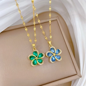Golden rotating flower necklaces with emerald and blue crystal petals on satin