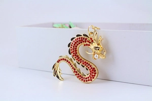 Vue macro du porte-clés dragon doré orné de strass rouges et d'une perle blanche
