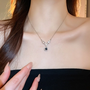 Dettaglio della collana con gemma nera quadrata e zirconi a V sulla clavicola