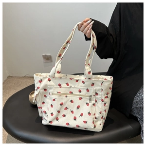 Detail of white corduroy tote bag with red strawberry pattern and exterior zipper pocket