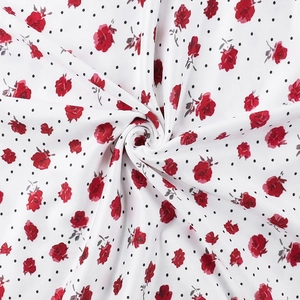 Primer plano de tela blanca floral con rosas rojas y lunares negros para vestidos