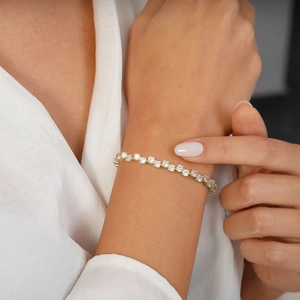 Detail of a gold tennis bracelet with white cubic zirconia stones on a female wrist