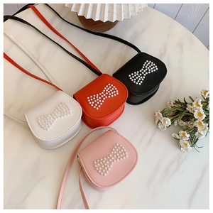Mini crossbody bags for kids in white, red, black, and pink with pearl bow details