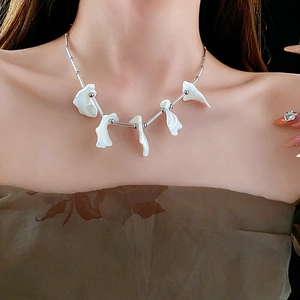 Dettaglio della collana con nappina in madreperla e catena d'argento su una modella