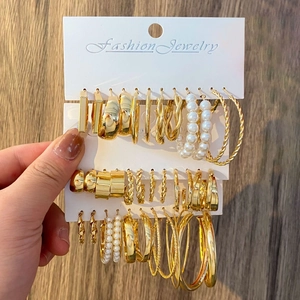 Close-up of gold-plated earring set featuring pearls and hoops on a display card