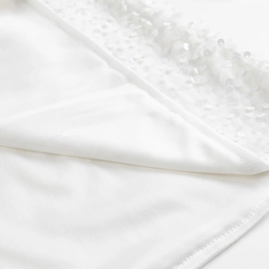 Gros plan sur les paillettes blanches et la texture soyeuse de la robe courte