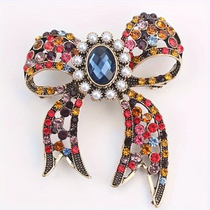 Vintage bow brooch with blue gemstone, pearls and colorful rhinestones on white background