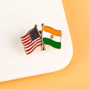 Detail of enameled metal pin featuring crossed USA and India flags on a white ceramic tray