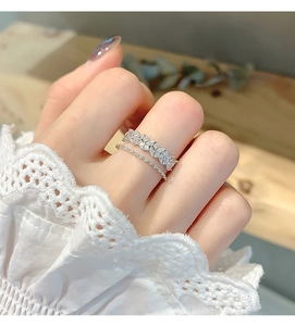 Detail of double-layered silver ring featuring zircon petals and twisted rope design