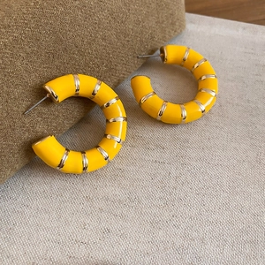 Detail of yellow enamel C-shaped hoop earrings with gold metal ribbon accents