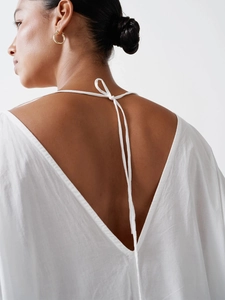 Detail of white cotton dress showing deep V-back design with delicate self-tie strings