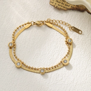 Elegantes goldfarbenes doppellagiges Edelstahlarmband mit weißen Zirkonia auf Vintage-Papier