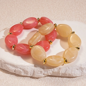 Detail of pink and beige acrylic oval link bracelets on a white textured stone base