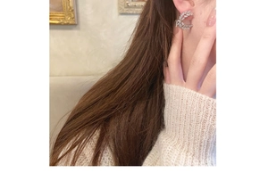 Close-up of elegant leaf-shaped silver earrings with sparkling stones on a model
