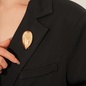 Poliertes Gold-Tropfenbrosche an schwarzem Revers zeigt elegantes Metalldetail