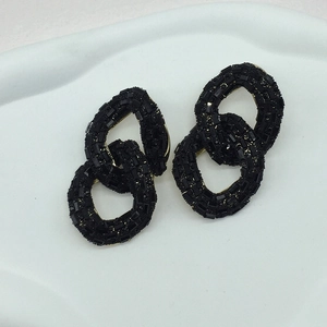 Detail of interlocking chain link earrings with micro-set black stones and gold accents