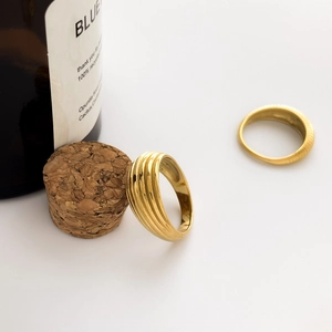 Detailed view of layered gold rings with elegant wave pattern texture on a minimalist base