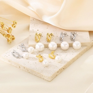 Detailansicht eleganter Perlenohrringe in Gold und Silber auf minimalistischem Stein-Hintergrund