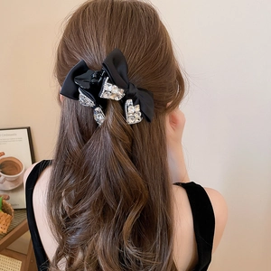 Dettaglio della pinza per capelli con fiocco in raso nero e strass scintillanti