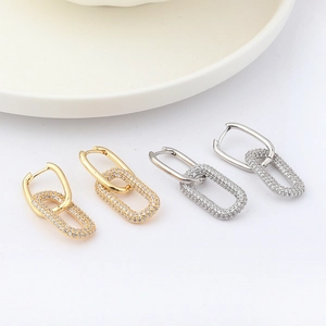Detail of gold and silver U-shaped hoop earrings with sparkling zircon oval links