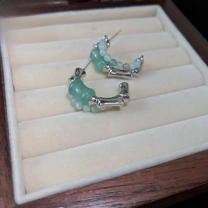 Detailed view of silver bamboo joint earrings with green jade beads on beige velvet