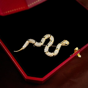 Macro shot of gold snake brooch with white zircons on black velvet jewelry box lining