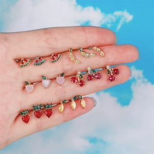 Macro shot of colorful zircon fruit stud earrings held by hand against a blue sky background