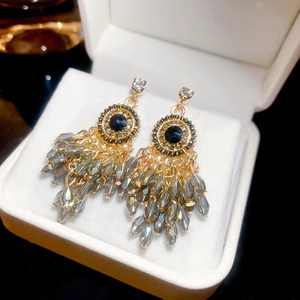 Detail of vintage round earrings with blue crystal, silver needles, and grey beaded tassels