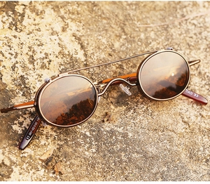 Detail view of steampunk round sunglasses with bronze frame on rustic rock background