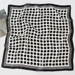 Polka dot silk scarf with striped border showing soft texture on a white surface