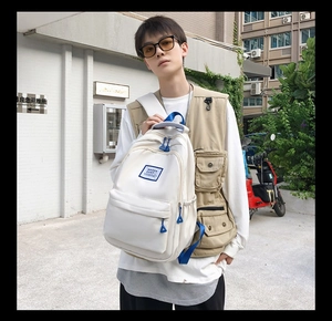 Detail of a large cream canvas backpack with blue accents and March Casp logo label